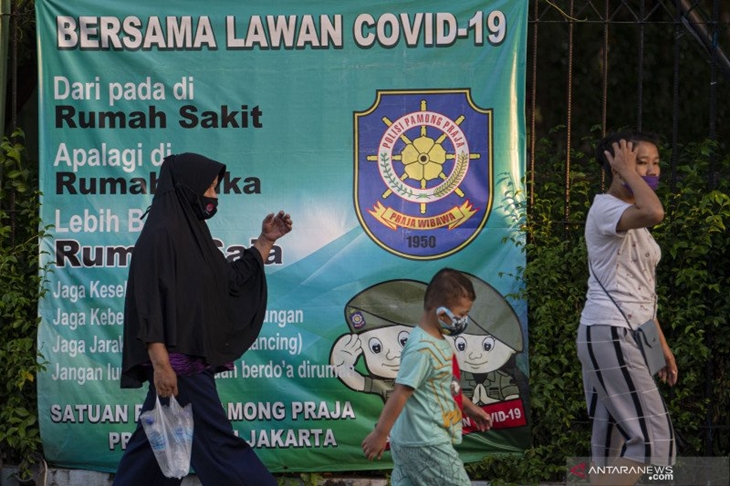 Sejumlah warga dengan mengenakan masker berjalan dengan latar belakang spanduk peringatan bahaya COVID-19 di Sunter, Jakarta, Sabtu (22/8/2020). Data Satuan Tugas Penanganan COVID-19 per hari Sabtu (22/8) pukul 12.00 WIB menyebutkan kasus positif COVID-19 bertambah 2.090 orang sehingga menjadi 151.498 orang, sementara kasus pasien sembuh COVID-19 bertambah 2.207 orang menjadi 105.198 orang. ANTARA FOTO/Aditya Pradana Putra/wsj.
