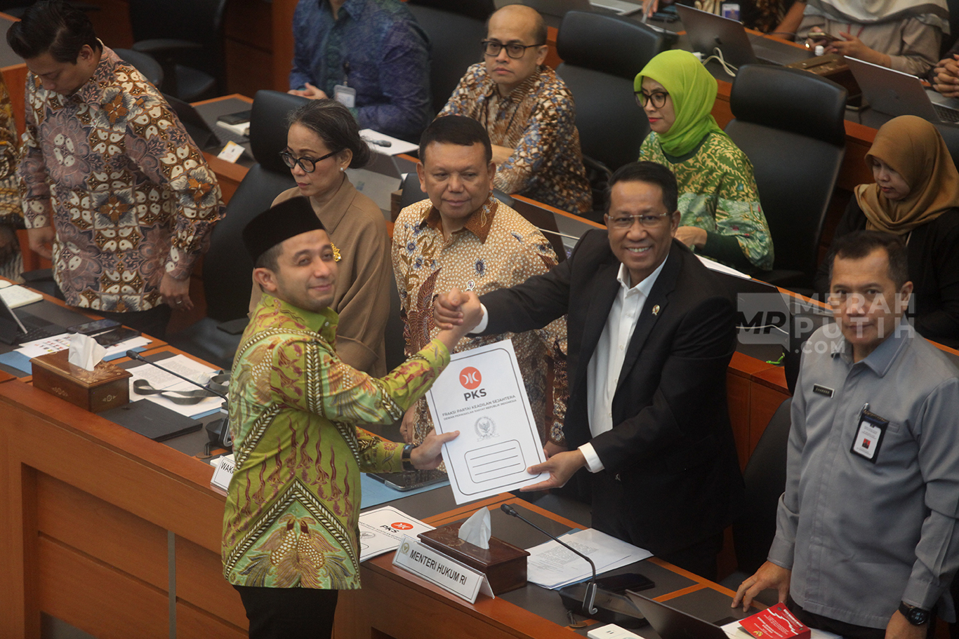 Perwakilan Fraksi PKS menyerahkan padangan mini fraksi kepada Menteri Hukum Supratman Andi Agtas (kanan) saat rapat persetujuan tingkat I RUU TNI di Kompleks Parlemen, Senayan, Jakarta, Selasa (18/3/2025).