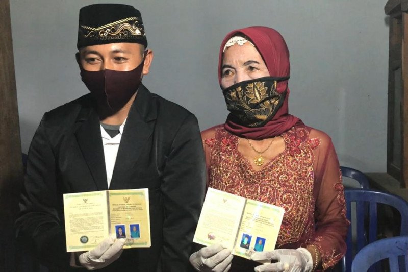 Ali Nursyahid (29) bersama pasangan yang baru dinikahi, Yainem (76) menunjukkan pernikahan usai acara ijab-qobul di kantir KUA Slahung, Ponorogo, Sabtu (28/11) (Antara/IST)