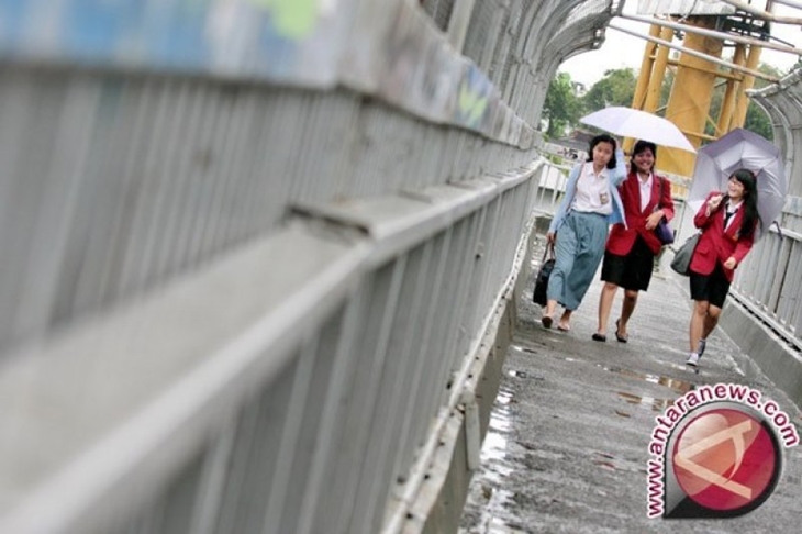 Warga mengenakan payung saat hujan ringan mengguyur Kawasan Pancoran, Jakarta. BMKG memprakirakan wilayah Jakarta, Bogor, Depok, Tangerang, dan Bekasi (Jabodetabek) akan diguyur hujan dengan intensitas ringan. (FOTO ANTARA/Dhoni Setiawan)
