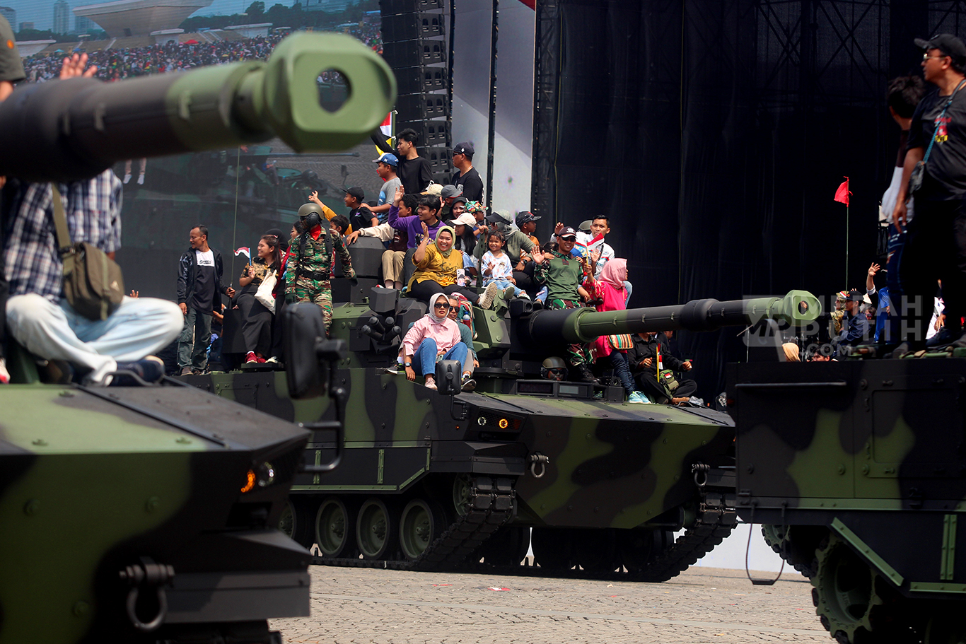 Wajah bahagia warga naik Tank Lapis Baja dalam parade defile alat utama sistem senjata (alutsista) milik TNI dalam peringatan Hari Ulang Tahun (HUT) ke-79 TNI di Lapangan Silang Monas, Jakarta Pusat, Sabtu (5/10/2024).