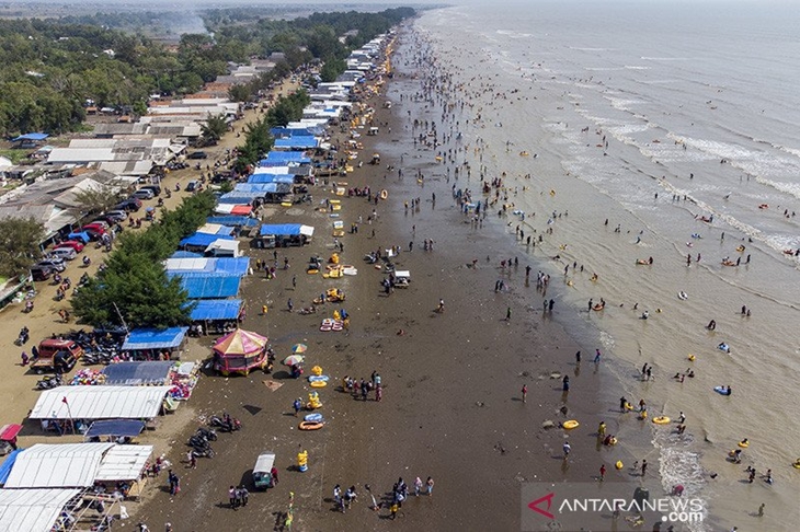 Foto udara wisatawan mengunjungi Pantai Tanjung Pakis di Desa Pakis Jaya, Karawang, Jawa Barat, Sabtu (15/5/2021). Menteri Pariwisata dan Ekonomi Kreatif Sandiaga Uno mengingatkan kepada pengelola tempat wisata di berbagai daerah untuk tetap menjalankan protokol kesehatan ketat agar angka kasus COVID-19 tidak mengalami peningkatan setelah libur Lebaran. ANTARA FOTO/M Ibnu Chazar/wsj.