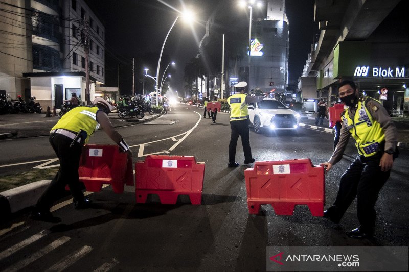 Petugas kepolisian menyusun pembatas jalan saat akan melakukan penutupan jalan dalam rangka pembatasan mobilitas warga guna menekan penyebaran COVID-19 di kawasan Bulungan, Jakarta, Senin (21/6/2021). Pembatasan tersebut dilakukan mulai pukul 21.00 WIB hingga 04.00 WIB di 10 titik di Kota Jakarta di antaranya Jalan Cikini Raya, kawasan Jalan Sabang, kawasan BKT, kawasan Kemang, PIK 2, kawasan Kota Tua dan Bulungan. ANTARA FOTO/Muhammad Adimaja/