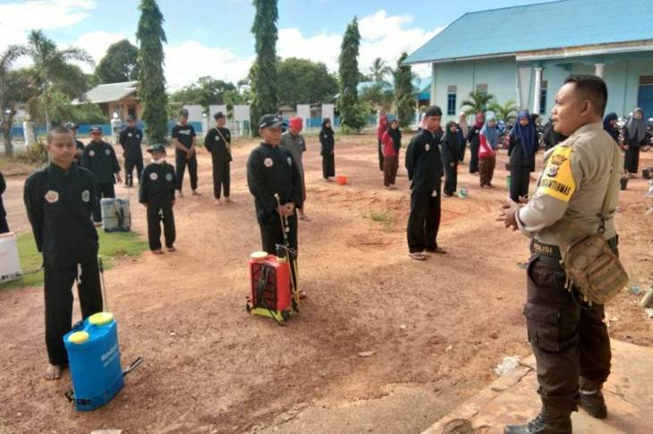 Babinkamtibmas Kampung Salor Bripka Heri Margo (kanan) sedang memberikan arahan kepada anggota perguruan pencak silat Pagar Nusa sebelum melaksanakan penyemprotan disinfektan dibeberapa tempat di Kampung Salor, Distrik Kurik, Merauke, Papua. (ANTARA /HO-Humas Polres Merauke)