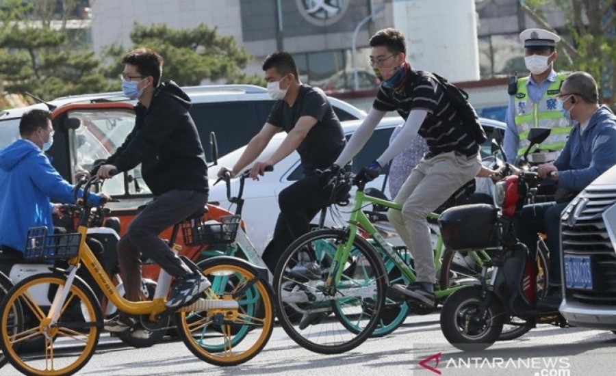Para warga menggunakan masker saat mengendarai sepeda dan motor di Beijing, China, Kamis (4/6/2020). REUTERS/The Yomiuri Shimbun/nz/djo    