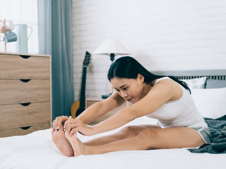 Perlahan tekuk pinggang dan raih tangan ujung jari kaki dengan tanganmu. (Foto: 123RF/primagefactory)