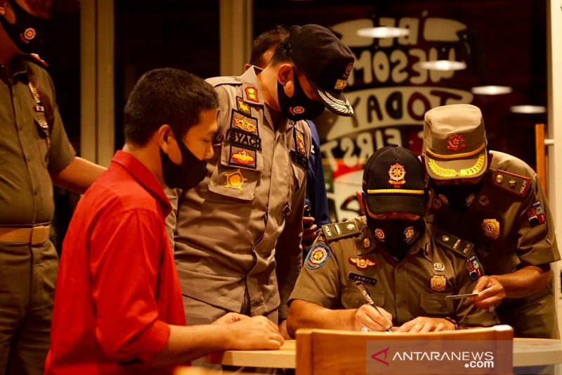 Tim Satpol PP memberikan sanksi denda kepada tempat usaha yang melanggar jam operasional melampaui pukul 18:00 WIB, pada razia yang dilakukan di Kota Bogor, Selasa (1/9/2020) malam. (ANTARA/HO/Pemkot