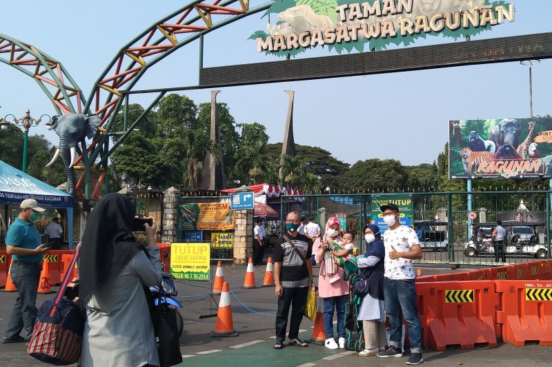 Calon pengunjung hanya bisa berfoto di depan pintu gerbang Taman Margasatwa Ragunan karena destinasi wisata itu tutup untuk penguatan protokol kesehatan dan dijadwalkan buka kembali pada Selasa (18/5) di Jakarta Selatan, Minggu (16/5/2021). (ANTARA/Dewa Ketut Sudiarta Wiguna)