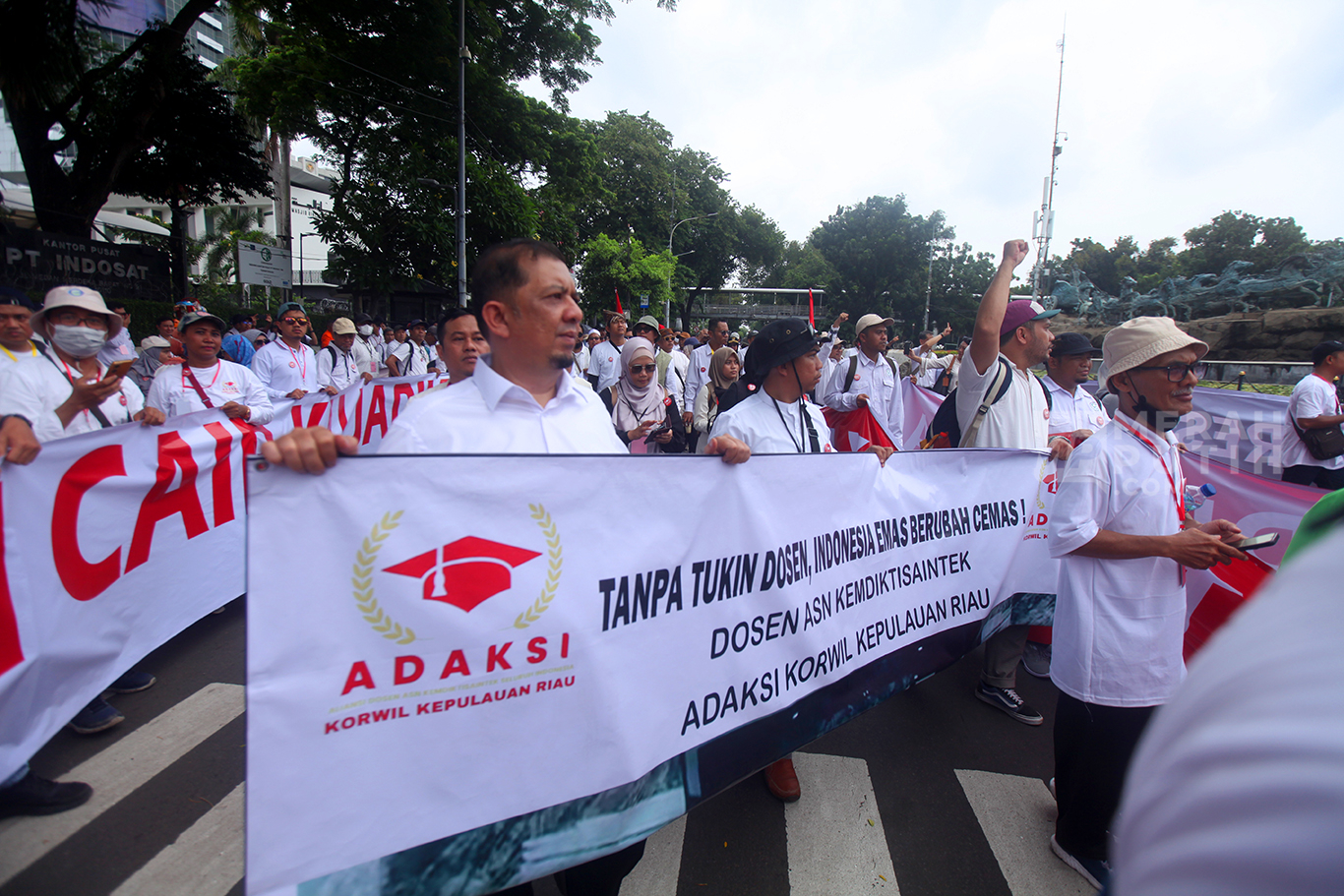 Dosen yang tergabung dalam Aliansi Dosen ASN Kemdiktisaintek Seluruh Indonesia (ADAKSI) membawa spanduk saat menggelar aksi di kawasan Patung Kuda, Jakarta, Senin (3/2/2025).