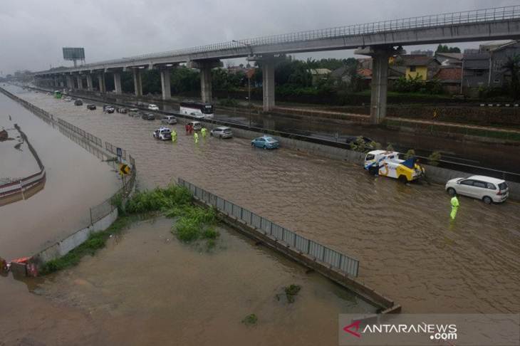 Petugas mengatur kendaraan yang melintasi genangan air ketika banjir merendam jalan Tol Cikampek di sekitar Jati Bening, Bekasi, Rabu (01/01/2020). Hujan lebat yang mengguyur Jakarta, Depok, Tangerang, dan Bekasi sejak malam hari menyebabkan sejumlah tempat di wilayah itu terendam air. ANTARA FOTO/Saptono/aww.