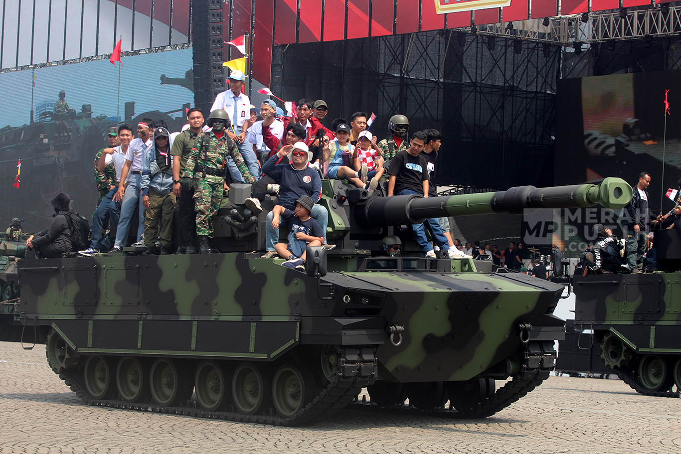 Wajah bahagia warga naik Tank Lapis Baja dalam parade defile alat utama sistem senjata (alutsista) milik TNI dalam peringatan Hari Ulang Tahun (HUT) ke-79 TNI di Lapangan Silang Monas, Jakarta Pusat, Sabtu (5/10/2024).