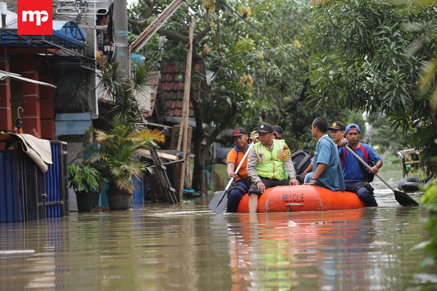 Tim gabungan BPBD dan Polri mengevakuasi warga perumahan Total Persada dengan menggunakan perahu karet, terbatasnya unit perahu karet membuat tim harus bekerja ekstra untuk mengevakuasi warga. Merahputih.com / Rizki Fitrianto