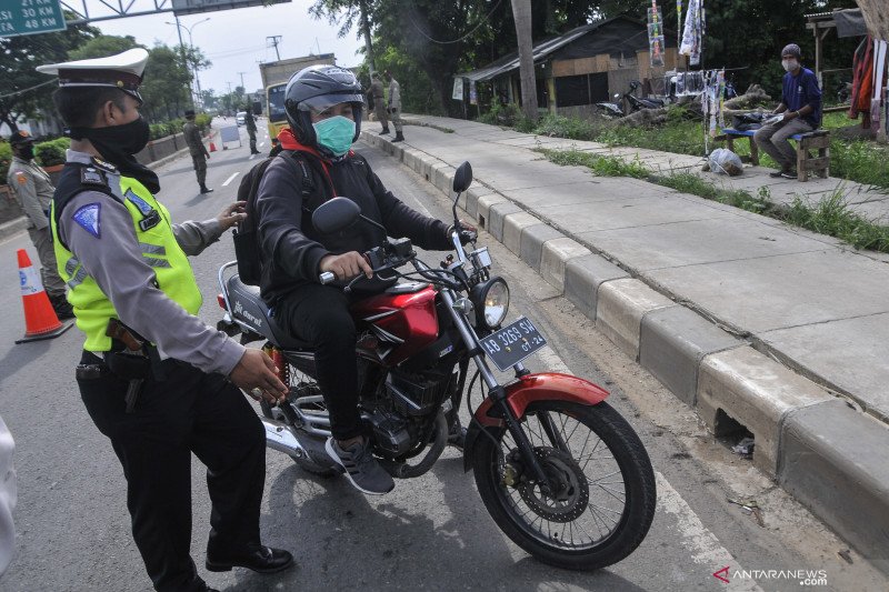 Polisi memberhentikan pengendara motor yang melintas di perbatasan Bekasi dengan Karawang daerah Kedungwaringin, Kabupaten Bekasi, Jawa Barat, Sabtu (25/4/2020). Hari kedua penerapan larangan mudik banyak pengendara yang tidak menerapkan jarak sosial dan tidak menggunakan masker. ANTARA FOTO/ Fakhri Hermansyah/pras. (ANTARA FOTO/Fakhri Hermansyah)