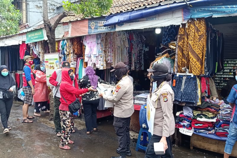 Polisi membagikan masker di Pasar Balimester Jatinegara, Jakarta Timur, dalam rangka program "Jakarta Bermasker", Minggu (14/2/2021). (ANTARA/Andi Firdaus)