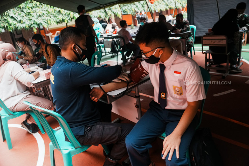 Petugas melakukan skrining kepada pelajar sebelum menyuntikan vaksin Covid-19 Sinovac saat Vaksinasi Massal Pelajar Serentak di 14 Provinsi di SMAN 1 Kota Tangerang, Banten, Rabu, (14/7/2021). Badan Intelejen Negara (BIN) Provinsi Banten bersama Pemeritah Kota Tangerang dan TNI-POLRI menyelenggarakan vaksinasi massal pelajar guna mendukung program percepatan program vaksinasi nasional. Vaksinasi tersebut dilakukan serentak di 14 Provinsi yang tersebar di Indonesia. Merahputih.com / Rizki Fitrianto