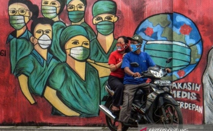 Pengendara motor melintas di depan mural tentang dukungan terhadap tenaga medis di Depok, Jawa Barat. (ANTARA FOTO/Yulius Satria Wijaya/pras)