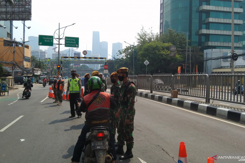 Petugas mengatur lalu lintas saat penyekatan di jalan lintas bawah Mampang Prapatan arah Jalan Rasuna Said, Jakarta Selatan, Kamis (15/7/2021). (ANTARA/Dewa Ketut Sudiarta Wiguna)