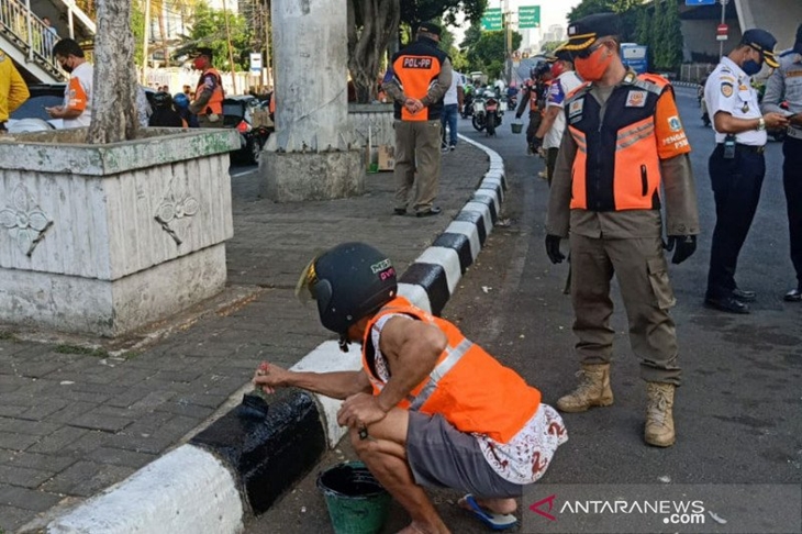 Warga yang tidak menggunakan masker terjaring dalam operasi Tibmask di Petamburan dan melakukan sanksi sosial mengecat tembok pembatas trotoar di Petamburan, Rabu (9/9/2020) (ANTARA/HO/dokumentasi Satpol PP Tanah Abang)
