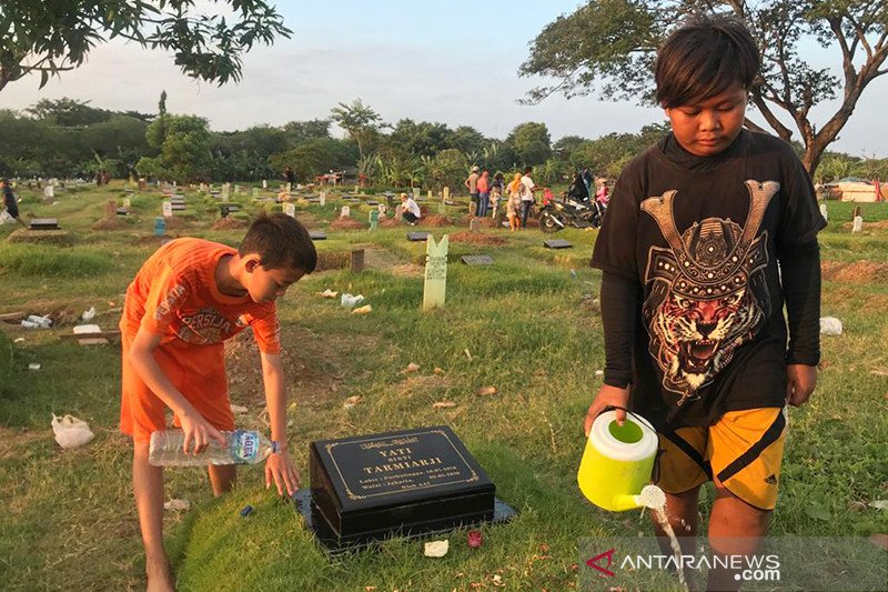 Anak-anak penyiram makam yang lazim ditemui saat ziarah Ramadhan di TPU Tegal Alur Kalideres, Jakarta, Minggu (11/4/2021). ANTARA/Devi Nindy/aa.