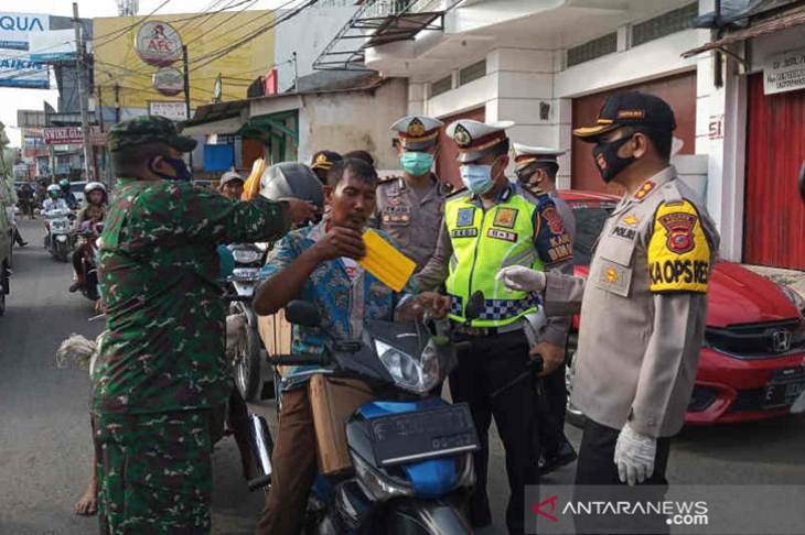 Kapolres Indramayu AKBP Suhermanto (kanan) saat memberikan masker kepada pengemudi sepeda motor yang tidak mengenakan masker saat keluar. (ANTARA/Khaerul Izan)