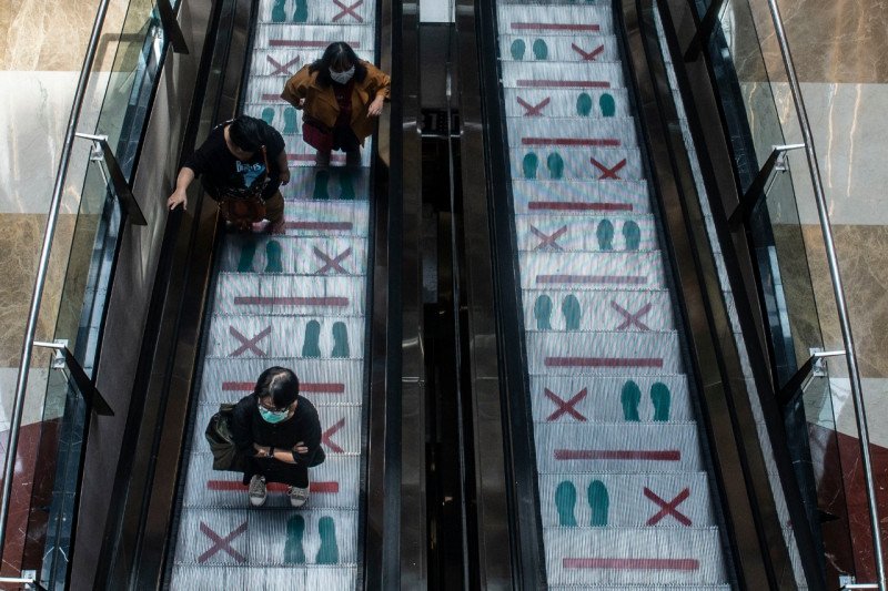 Pengunjung menaiki eskalator yang terpasang panduan jaga jarak fisik saat hari pertama pembukaan kembali pusat perbelanjaan di Pondok Indah Mall, Jakarta, Senin (15/6/2020). (ANTARA FOTO/Aprillio Akba