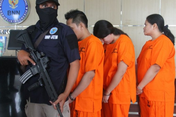 Petugas Badan Narkotika Nasional Provinsi Jawa Timur membawa tersangka saat pemusnahan barang bukti narkotika di Surabaya Selasa (11/2)/Foto Antara/Didik Suhartono