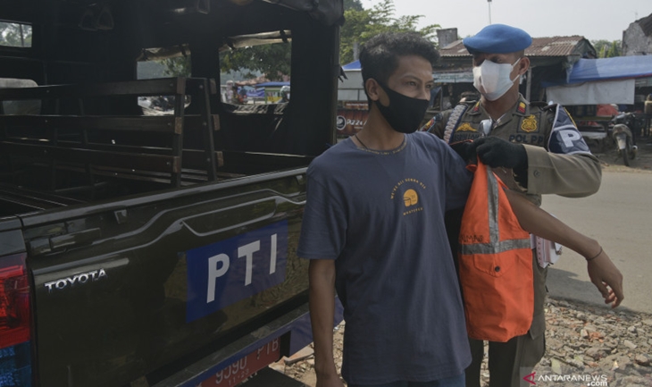 Petugas Satpol PP Jakarta Timur memasangkan rompi pada warga yang melanggar protokol kesehatan. ANTARA FOTO/Paramayuda/hp