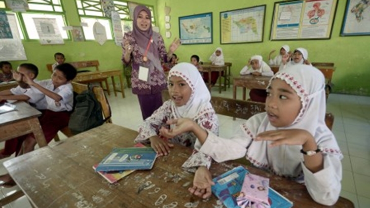 Seorang guru sedang mengajar di kelas