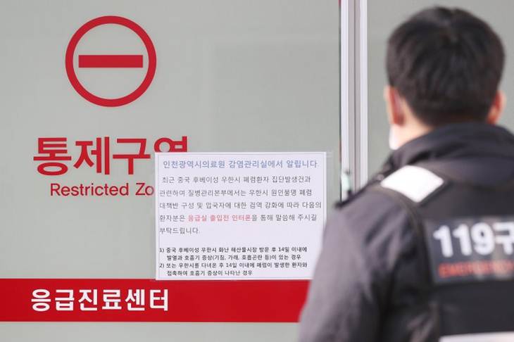 Seorang anggota tim penyelamat berjalan melewati sebuah pengumuman tentang virus corona baru telah menyebar di China, di sebuah rumah sakit dimana seorang perempuan warga China, yang terbang dari Wuhan, China dan telah dikonfirmasi sebagai kasus pertama virus corona baru, di isolasi, di Incheon, Korea Selatan, Senin (20/1/2020). (REUTERS/STRINGER)