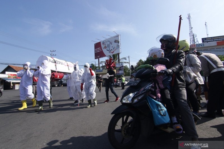 Pemudik melihat aksi teaterikal bahaya COVID-19 oleh anggota Satlantas Polresta Banyuwangi di Pos Check Point Penyekatan Antar Provinsi di Pelabuhan Ketapang, Banyuwangi, Jawa Timur, Sabtu (22/5/2021). ANTARA FOTO/Budi Candra Setya/foc.