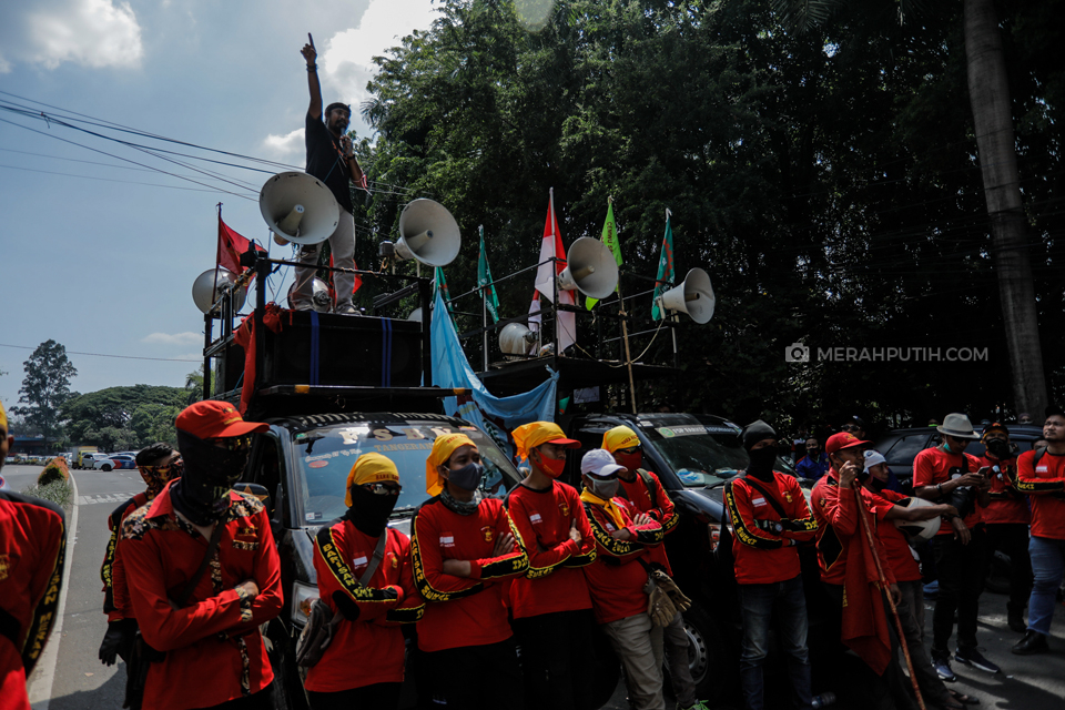 Ratusan buruh melakukan unjuk rasa dengan memblokade jalan utama Kota Tangerang sebagai wujud penolakan Rancangan Undang-Undang (RUU) Omnibus Law Cipta Kerja di depan kantor Dinas Ketenagakerjaan Kota Tangerang, Kota Tangerang, Banten, Senin, (5/10/2020). Pihak Kepolisian melakukan menyekatan di sejumlah titik pada massa buruh dari Tangerang menuju Gedung DPR RI di Jakarta. Sejumlah buruh memang mengagendakan akan menggelar aksi unjuk rasa di depan DPR selama beberapa hari ke depan, hingga 8 Oktober 2020. Merahputih.com / Rizki Fitrianto