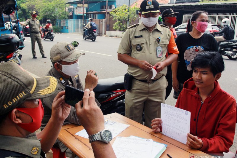 Petugas mendata warga yang kedapatan tidak mengenakan masker saat digelar razia penerapan Pembatasan Sosial Berskala Besar (PSBB) Total di wilayah perbatasan DKI Jakarta. ANTARA FOTO/Muhammad Iqbal