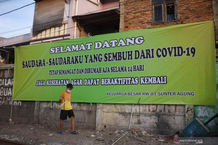 Seorang anak berjalan di depan spanduk selamat pasien virus corona (COVID-19) yang dinyatakan sembuh di RW 01, Kamis (4/6/2020) (ANTARA/Fauzi Lamboka)