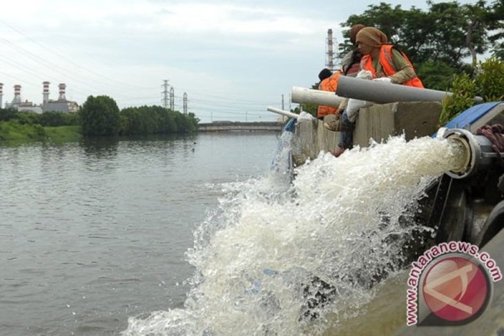 Seorang pria duduk di samping pipa mesin pompa pengendali banjir mobile di kawasan Pluit Indah, Jakarta Utara, Selasa (21/1). Melalui pipa-pipa, air banjir di kawasan tersebut kemudian dialirkan langsung ke Kali Pluit sehingga genangan banjir menjadi cepat surut. (ANTARA FOTO/Andika Wahyu)