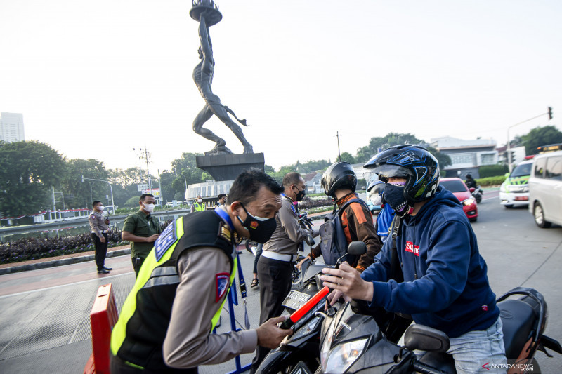 Anggota Polisi memeriksa identitas pengendara sepeda motor saat berlangsungnya Pemberlakuan Pembatasan Kegiatan Masyarakat (PPKM) Darurat di kawasan Bundaran Senayan, Jakarta, Sabtu (3/7/2021). Petugas akan memberikan akses untuk melintas di titik penyekatan PPKM Darurat di 63 titik di wilayah Jadetabek yang berlaku dari 3-20 Juli 2021 hanya yang masuk kategori sektor-sektor esensial. ANTARA FOTO/M Risyal Hidayat