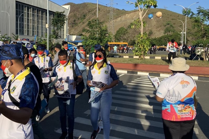 Panitia Besar Pekan Olahraga Nasional (PB PON) XX Papua tampak membagikan koran “Arena PON Papua” kepada para penonton yang akan menyaksikan upacara penutupan PON Papua di Lukas Enembe, Jumat (15/10/2021). (ANTARA/Arindra Meodia)