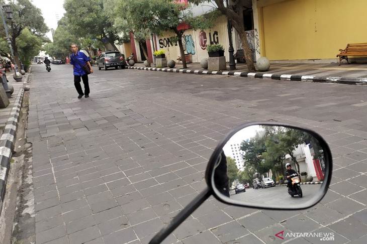 Seorang warga melintas jalan yang lengang di Jalan Braga, Kota Bandung, Senin (30/3/2020). (ANTARA/Bagus Ahmad Rizaldi)