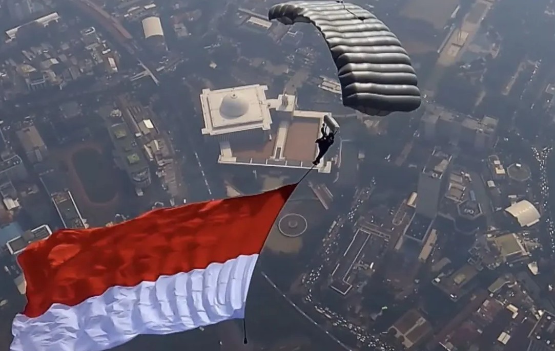 Spektakuler! 17 Penerjun Kopassus Kibarkan Merah Putih di Langit Monas