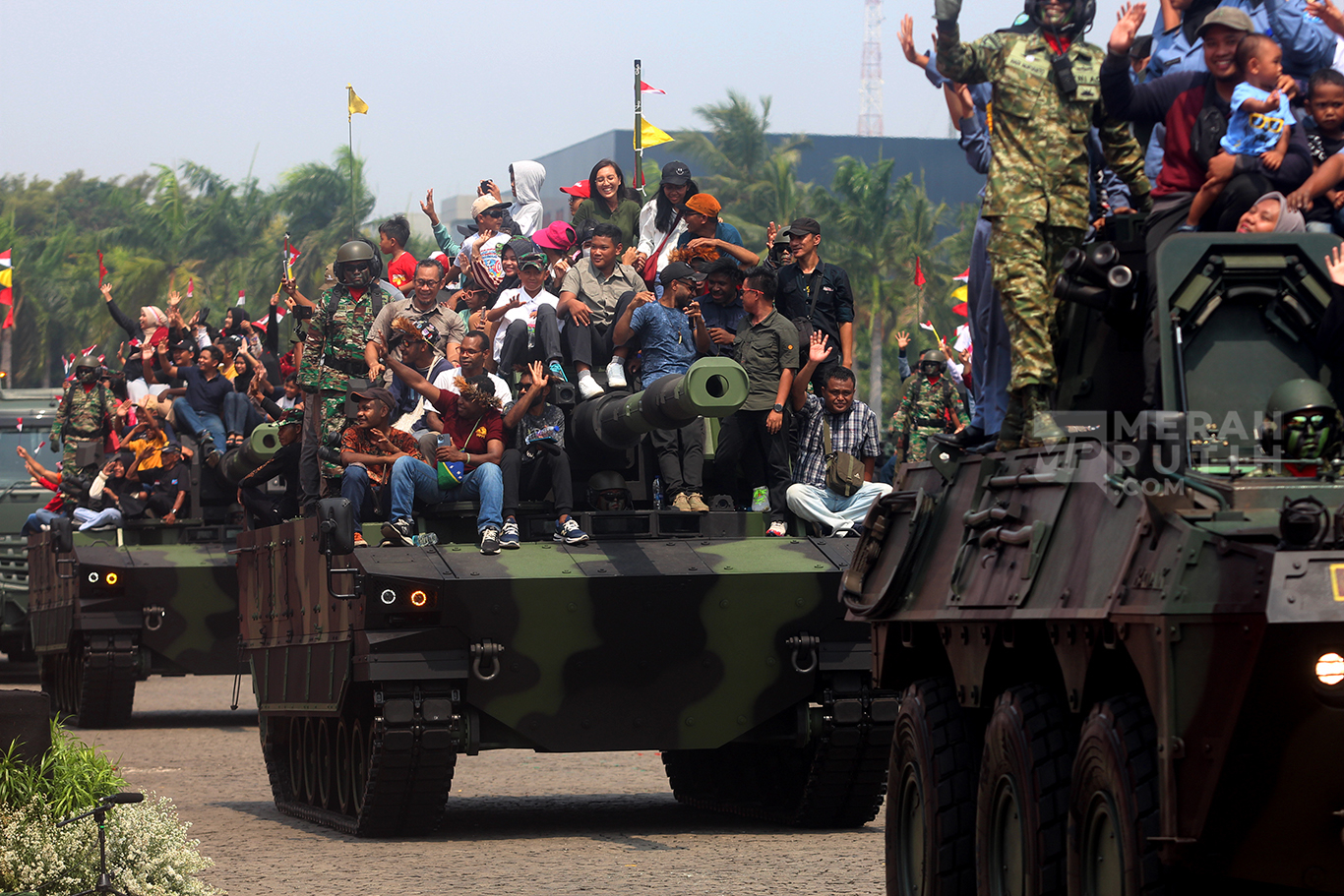 Wajah bahagia warga naik Tank Lapis Baja dalam parade defile alat utama sistem senjata (alutsista) milik TNI dalam peringatan Hari Ulang Tahun (HUT) ke-79 TNI di Lapangan Silang Monas, Jakarta Pusat, Sabtu (5/10/2024).