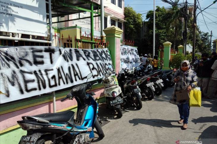 Seorang warga berjalan di depan spanduk tuntutan warga Kelurahan Warakas, Tanjung Priok, Jakarta Utara, Kamis (14/5/2020) (ANTARA/Fauzi Lamboka)