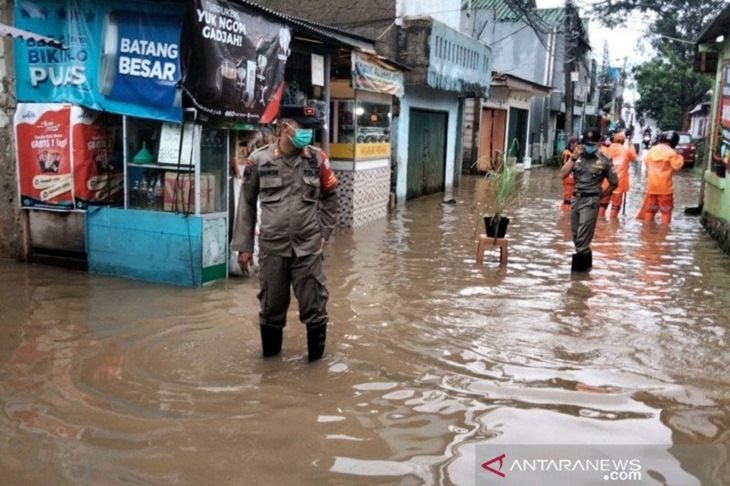 Petugas Satpol PP memantau genangan air yang terjadi di Jalan H Sulaiman, Cipinang Melayu, Kecamatan Makassar, Jakarta Timur, Selasa (16/2/2021). Genangan air terjadi akibat luapan saluran penghubung Sulaiman yang meluap. (ANTARA/HO-Satpol PP Makasar).