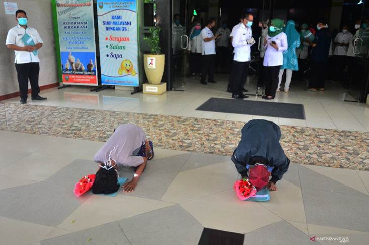 Arsip Foto. Dua pasien yang dinyatakan sembuh dari COVID-19 sujud syukur setelah menerima surat keterangan bebas COVID-19 di RSUD Loekmono Hadi, Kudus, Jawa Tengah, Kamis (14/5/2020). (ANTARA FOTO/YUSUF NUGROHO)