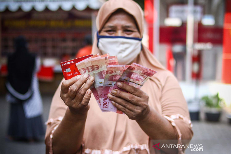 Warga menunjukkan uang bantuan sosial tunai atau BST usai mengambil di ATM Bank DKI, Jakarta, Selasa (20/7/2021). ANTARA FOTO/Rivan Awal Lingga/aww.