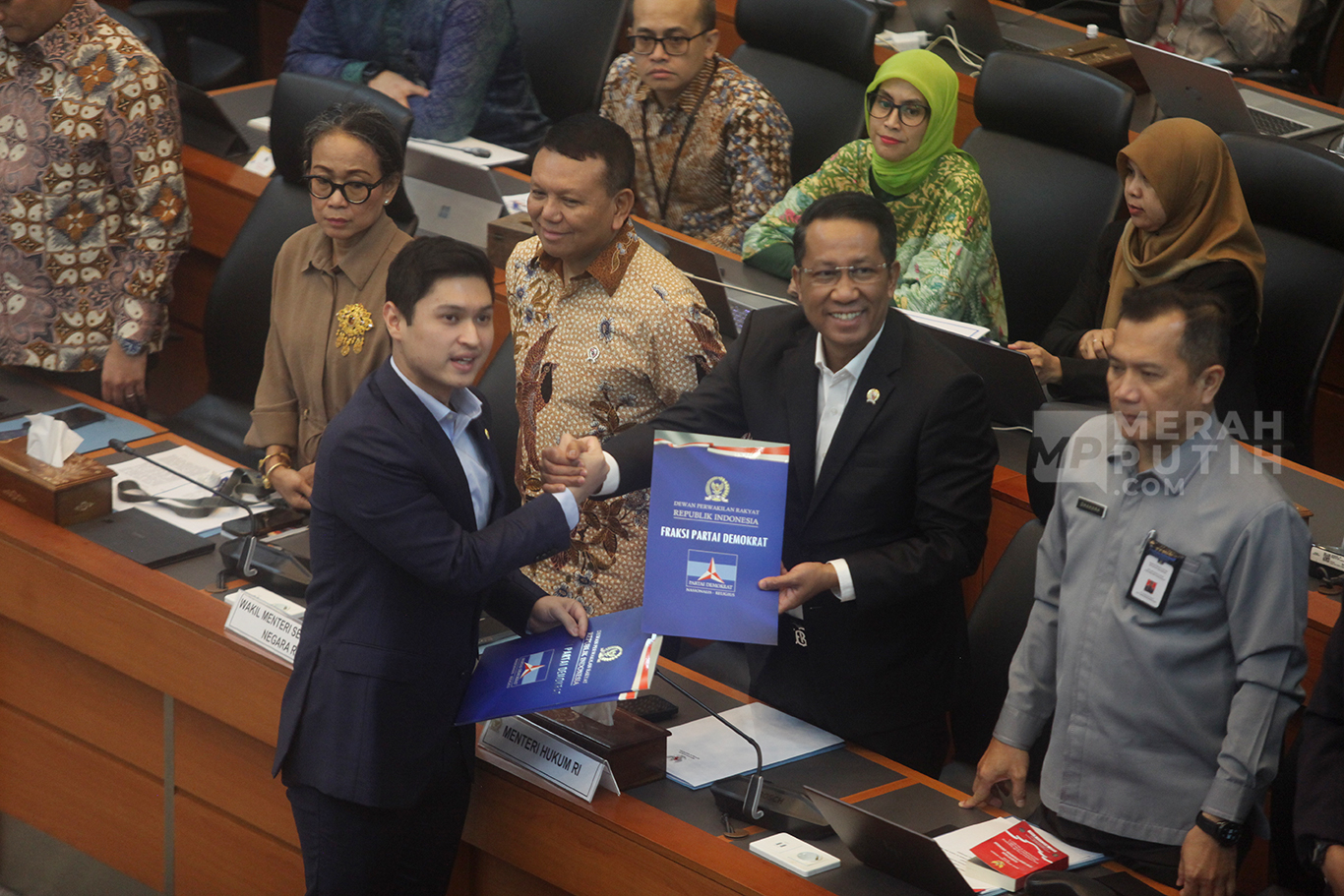 Perwakian Fraksi Demokrat, Rizki Natakusumah menyerahkan pandangan mini fraksi kepada Menteri Hukum Supratman Andi Agtas (kanan) saat rapat persetujuan tingkat I RUU TNI di Kompleks Parlemen, Senayan, Jakarta, Selasa (18/3/2025).