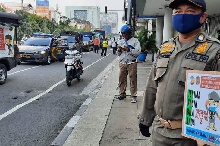 Seorang petugas Satpol PP Jakarta Barat menyosialisasikan aturan PSBB dalam patroli gabungan yang dilakulan di wilayah Tamansari, Sabtu (11/4/2020) (ANTARA/Laily Rahmawaty)