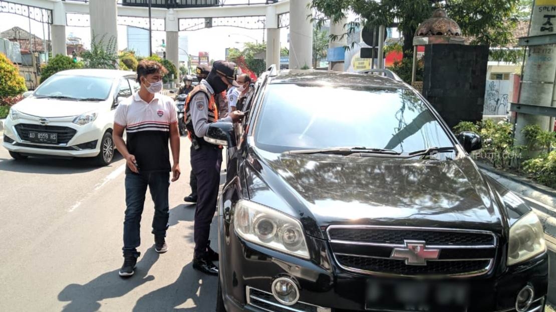  Petugas Polresta Surakarta dan Dishub Solo melakukan penyekatan kendaraan luar kota masuk wilayah Solo, Jawa Tengah di Jalan Adi Sucipto, Senin (27/4). (MP/Ismail)