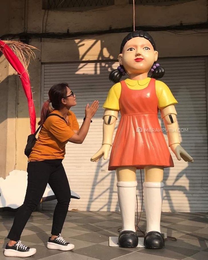 Pengguna Jalan Tunjungan berfoto di samping boneka Squid Game. (Foto: MP/Budi Lentera)