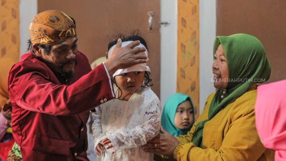 Mbah Sumanto mengenakan penutup kepala kepada anak gimbal sebelum ruwatan (MP/Rizky Fitrianto)