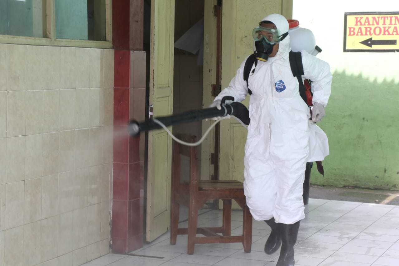 Petugas Pemkot Solo melakukan penyemprotan disinfektan di sekolah, Minggu (29/3). (MP/Ismail)