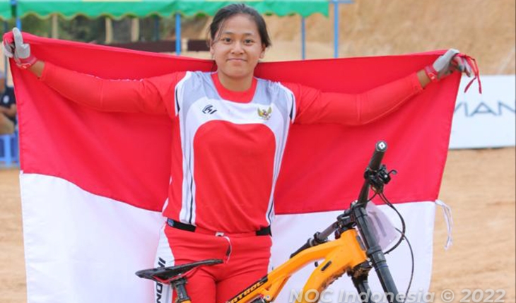 Tiara Andini mengibarkan bendera Merah Putih di depan sepedanya usai berhasil mempersembahkan emas untuk Indonesia dari Cycling MTB nomor Women's Mountain Bike Downhill Individual. (NOC Indonesia/Andi Faisal)